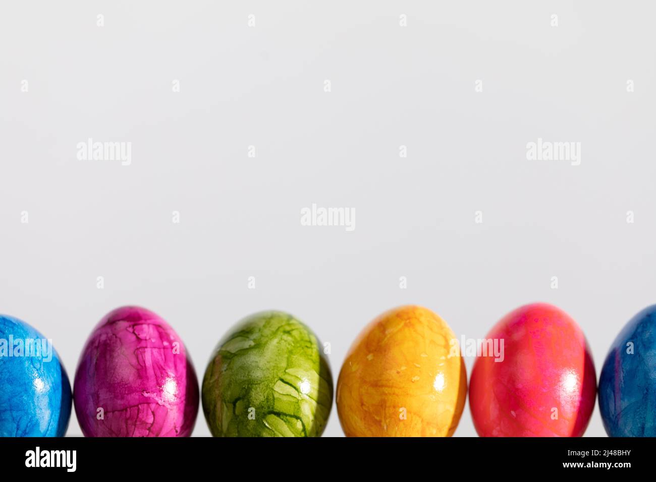 Many Easter eggs arranged in one row on a white background. Easter. Stock Photo