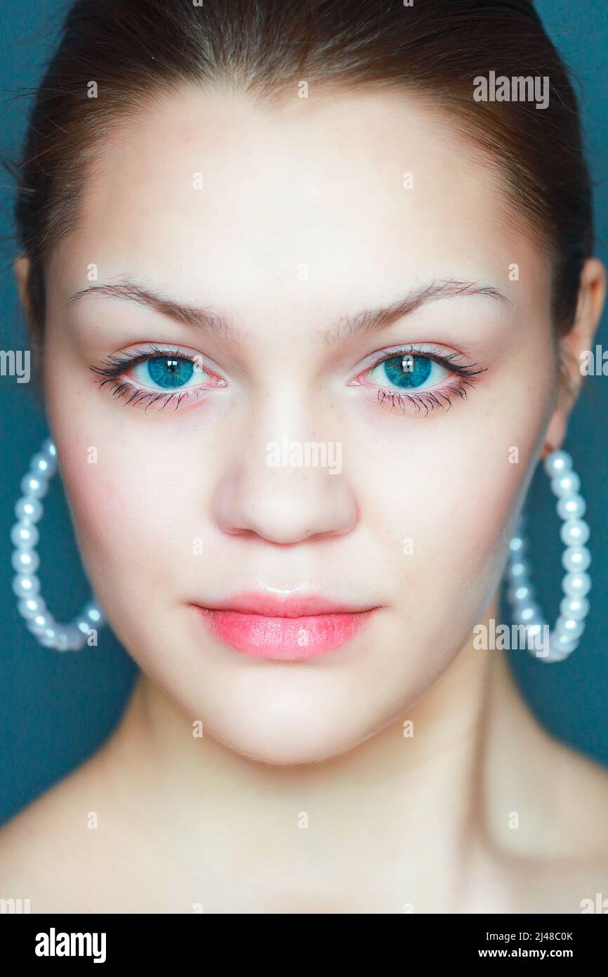 Face of young Caucasian model with smooth smooth skin and beautiful eyes. Front portrait of girl of 18-20 years old with confident and daring look. Stock Photo