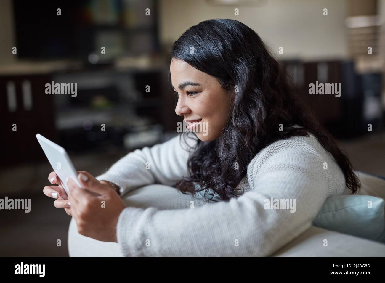 Updating all her favourite apps. Shot of an attractive young woman using a digital tablet at home. Stock Photo