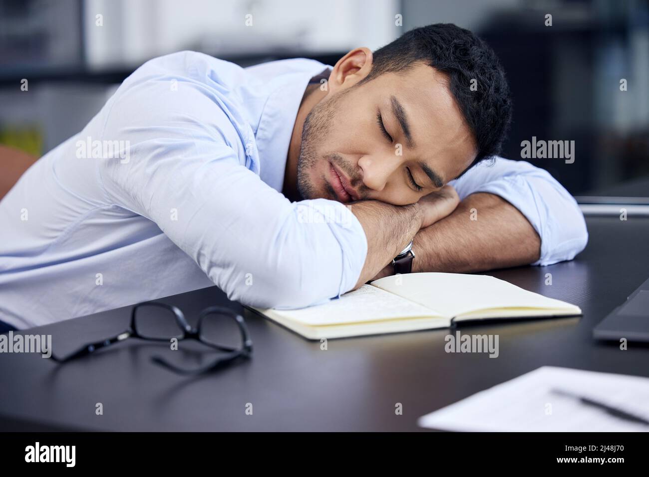 I just need a few minutes. Shot of an exhausted businessman having a quick nap on the desk at