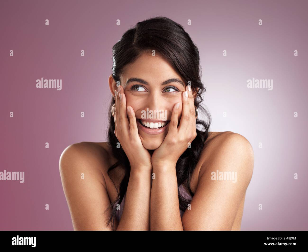 Dream big, stay focussed and make it happen. Shot of a beautiful young woman pondering with her hands rested her chin and face against a pink Stock Photo