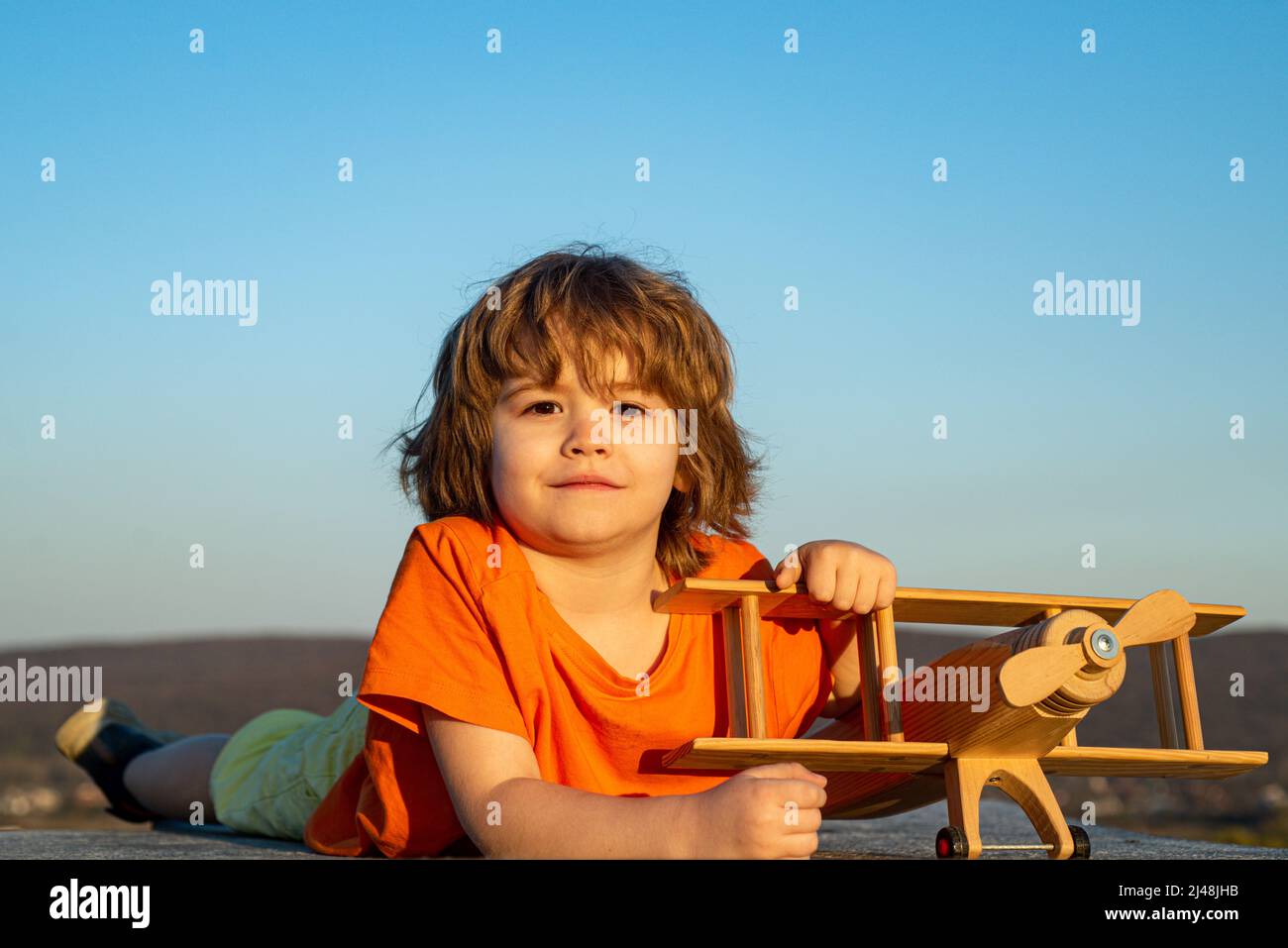 Happy kid playing with toy airplane against blue sky background. Cute ...