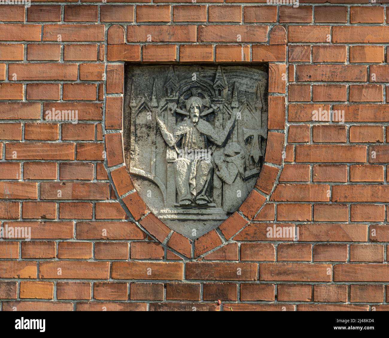 Architectural decorative detail, representing a seated Christ with a city behind him, set in a red brick wall. Odense, Fyn, Denmark, Europe Stock Photo