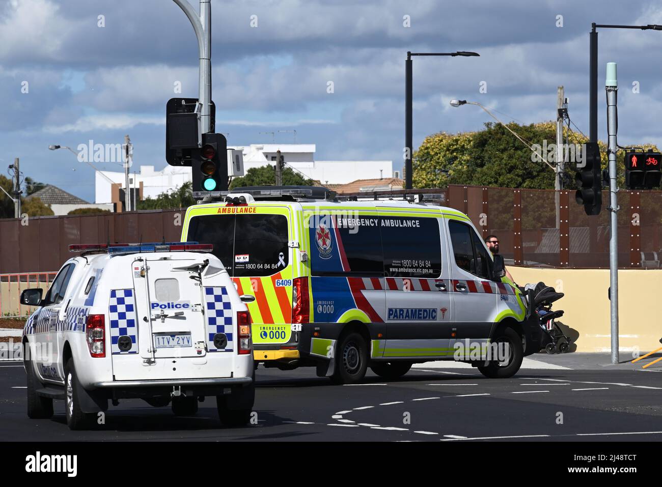Ambulance turning right at the corner of Station St and Edithvale Rd, towards Nepean Hwy, while being followed by a police vehicle Stock Photo