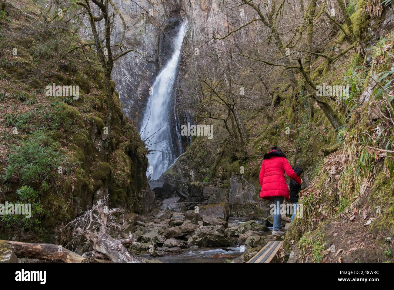 People walking along a slippery path leading to Gray Mare's Tail, one of the most impressive waterfalls in Scotland, UK Stock Photo