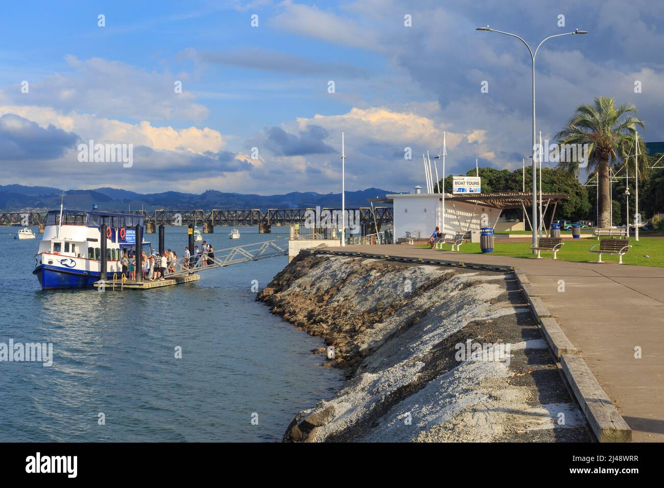 Tauranga, New Zealand. View of a waterfront park and a tour boat, the 'Kewpie', docked in Tauranga Harbour Stock Photo
