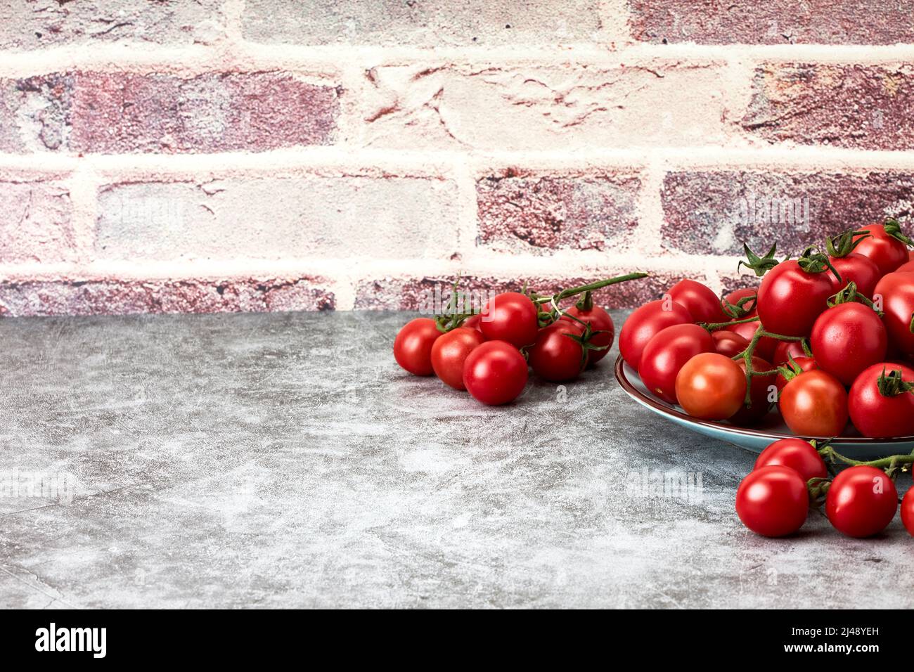 Composition of ripe cherry tomatoes on a plate on a stone countertop. Healthy food. Vegan food. Vegetarian food Stock Photo