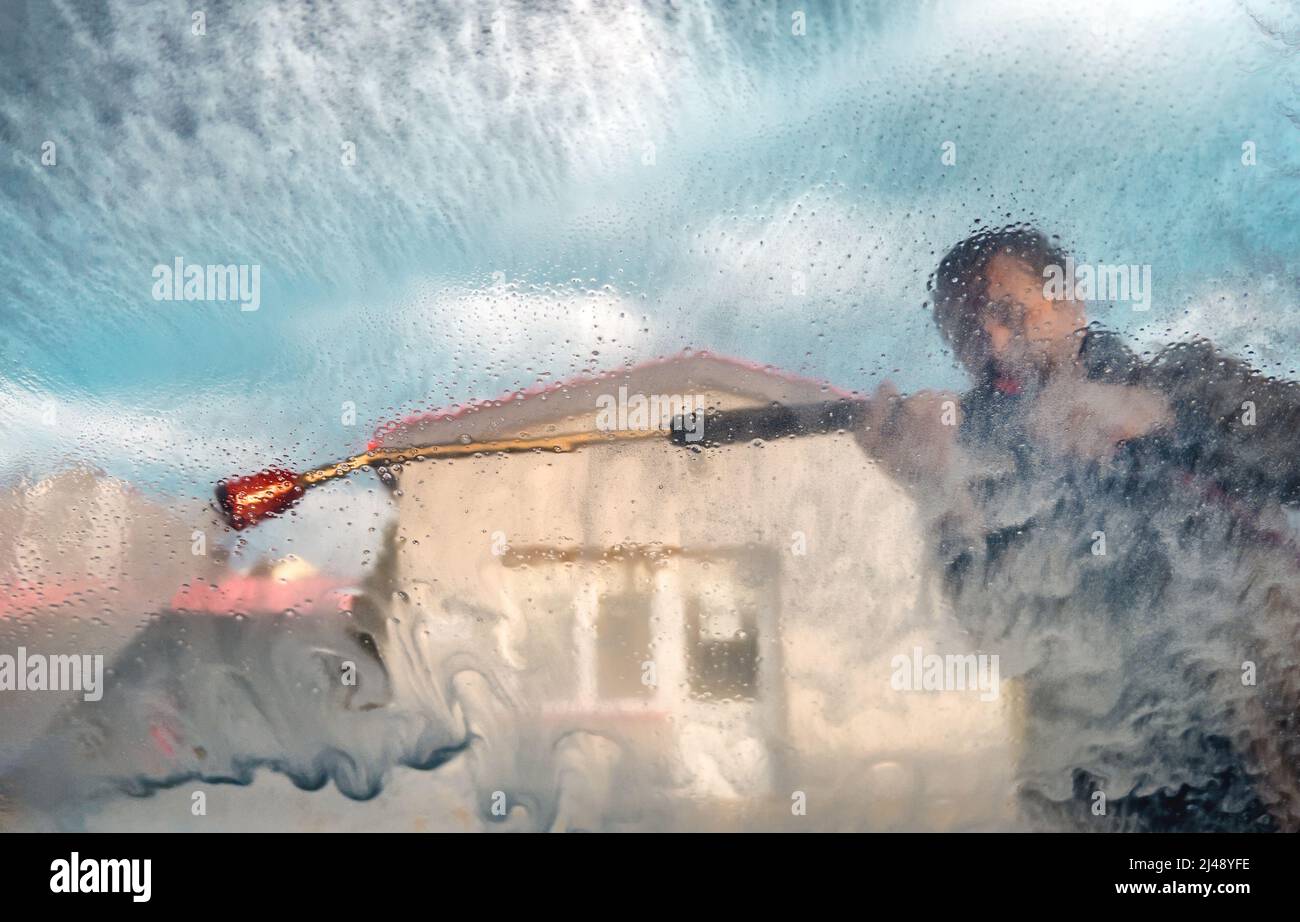 Man using water gun jet sprayer in car wash self-service, selective focus Stock Photo