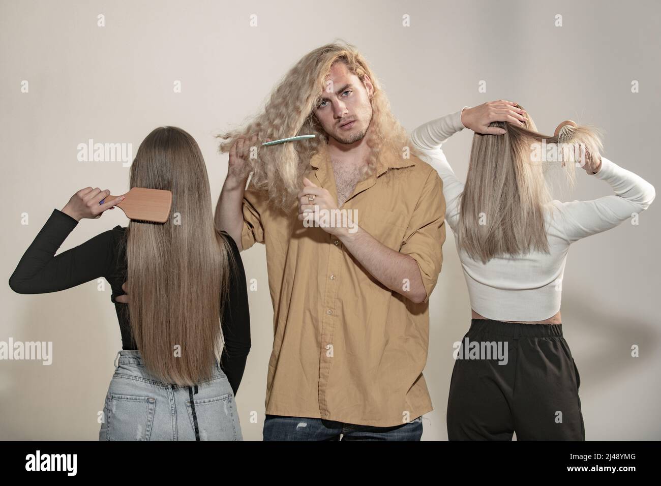 Man brushing curly hair, woman combing straight hair. Group of young
