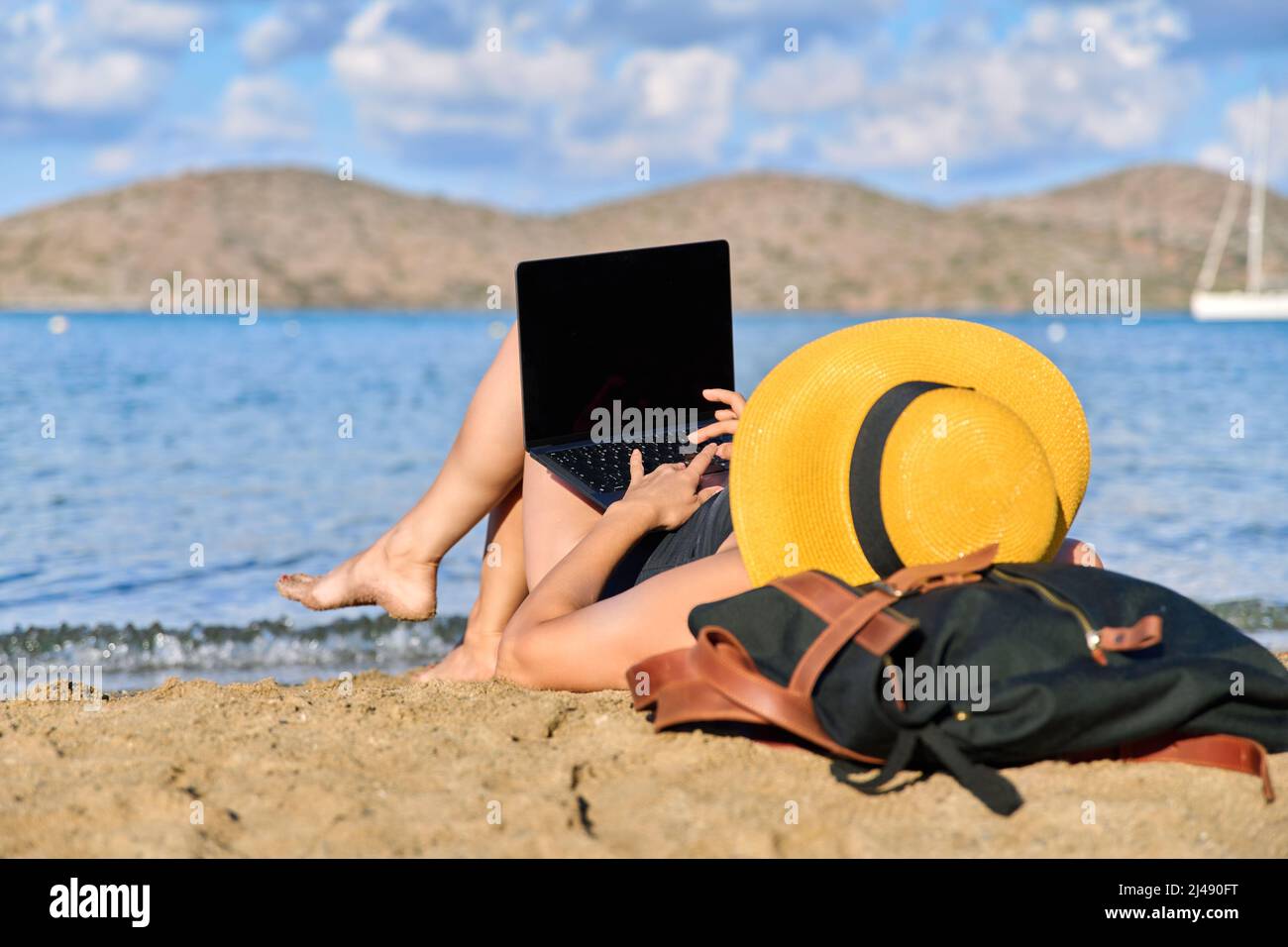 Mature woman sunbathing on the beach using a laptop Stock Photo - Alamy