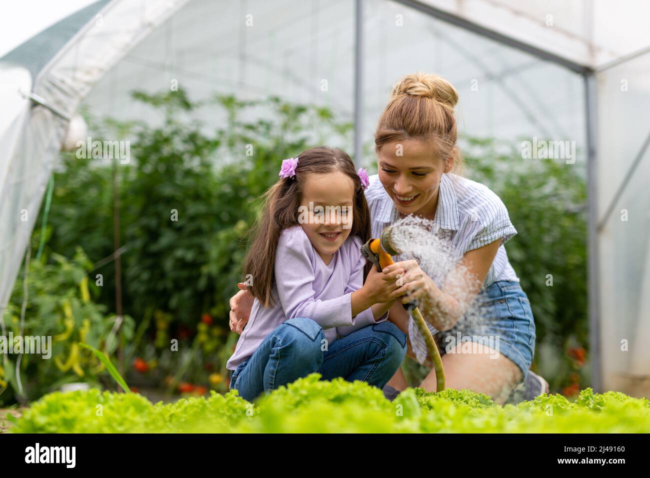 Happy family working in organic greenhouse. Woman and child growing bio