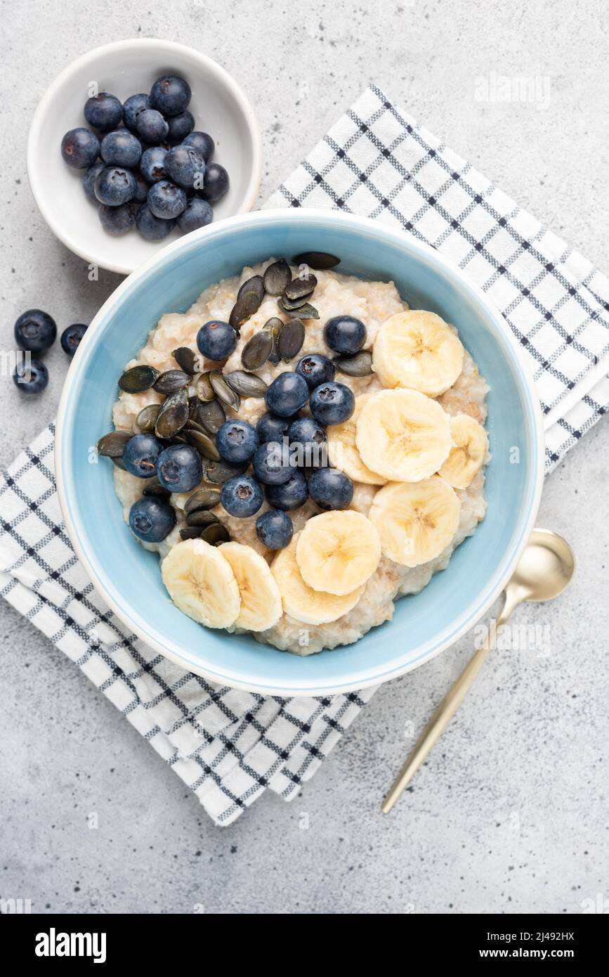 Oatmeal bowl with blueberries, banana slices and pumpkin seeds. Top view. Healthy breakfast food for diet, weight loss, clean eating Stock Photo