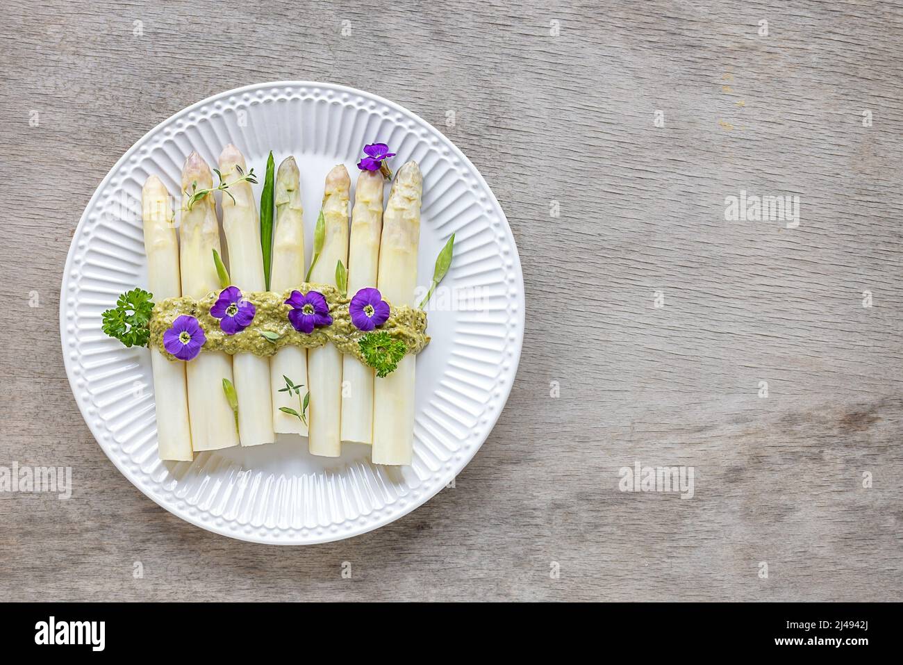 White asparagus with italian pesto sauce and edible flowers. Stock Photo