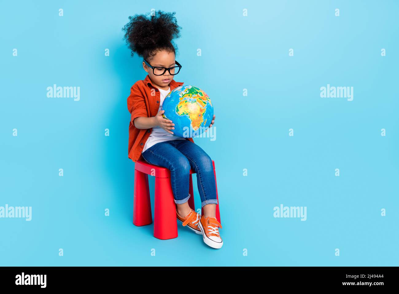 Full body photo of focused concentrated interested little girl studying geography isolated on blue color background Stock Photo