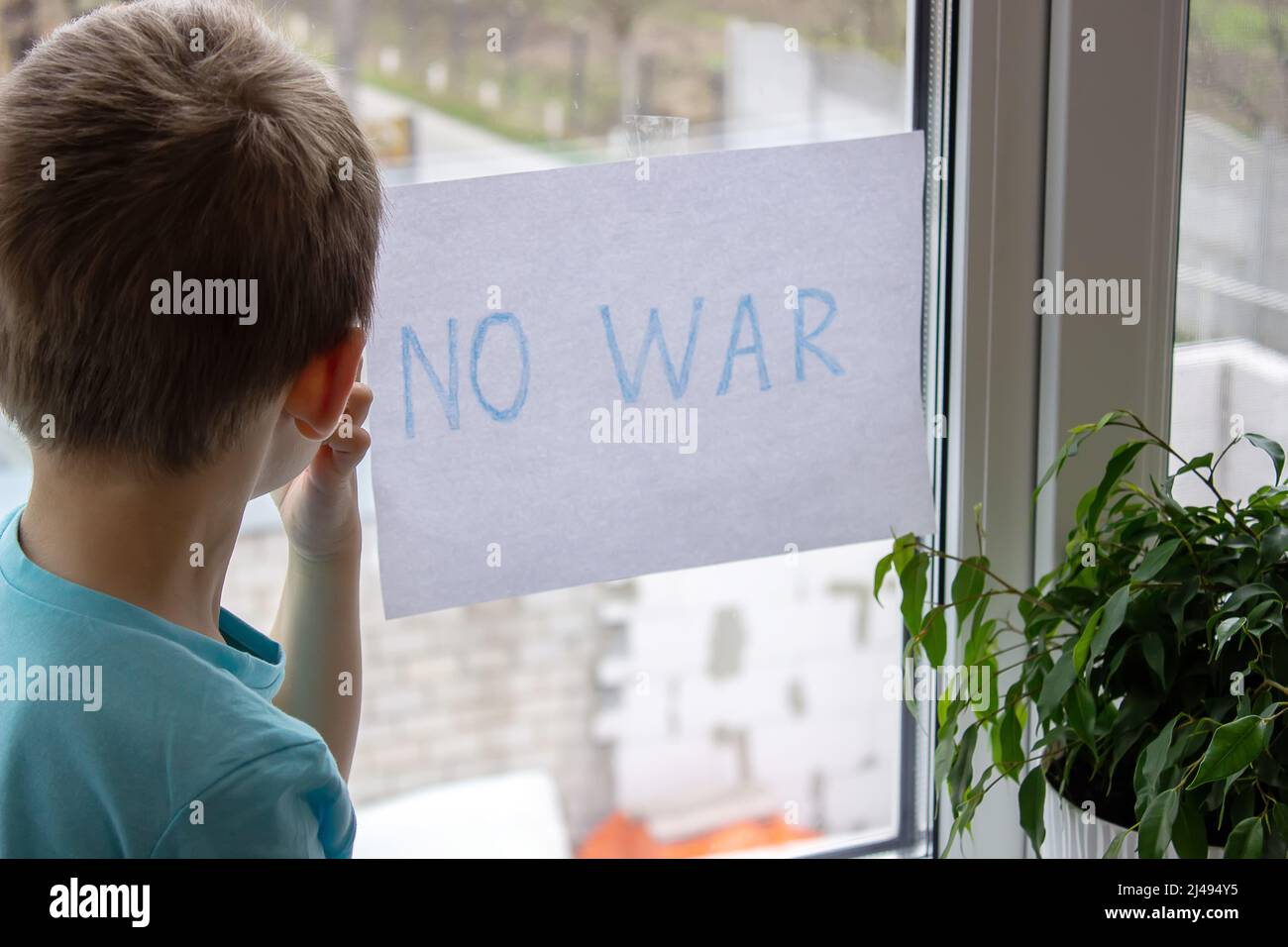 a little boy is holding a piece of paper on which is written no to war. selective focus Stock Photo