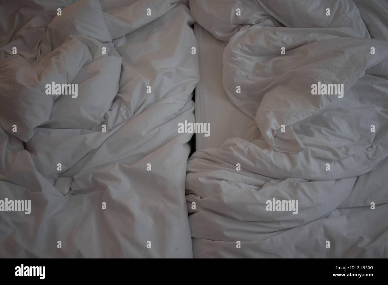 Top view of twin beds with unmade, crinkled bedding, white sheets