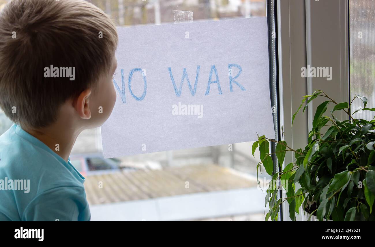 a little boy is holding a piece of paper on which is written no to war. selective focus Stock Photo