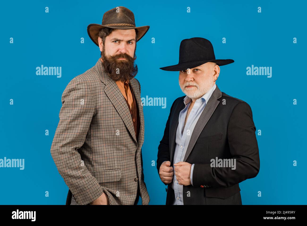 Head shot portrait of elderly mature senior dad and grownup son. Two male generations family. Men in hat. Men in different ages in studio. Stock Photo