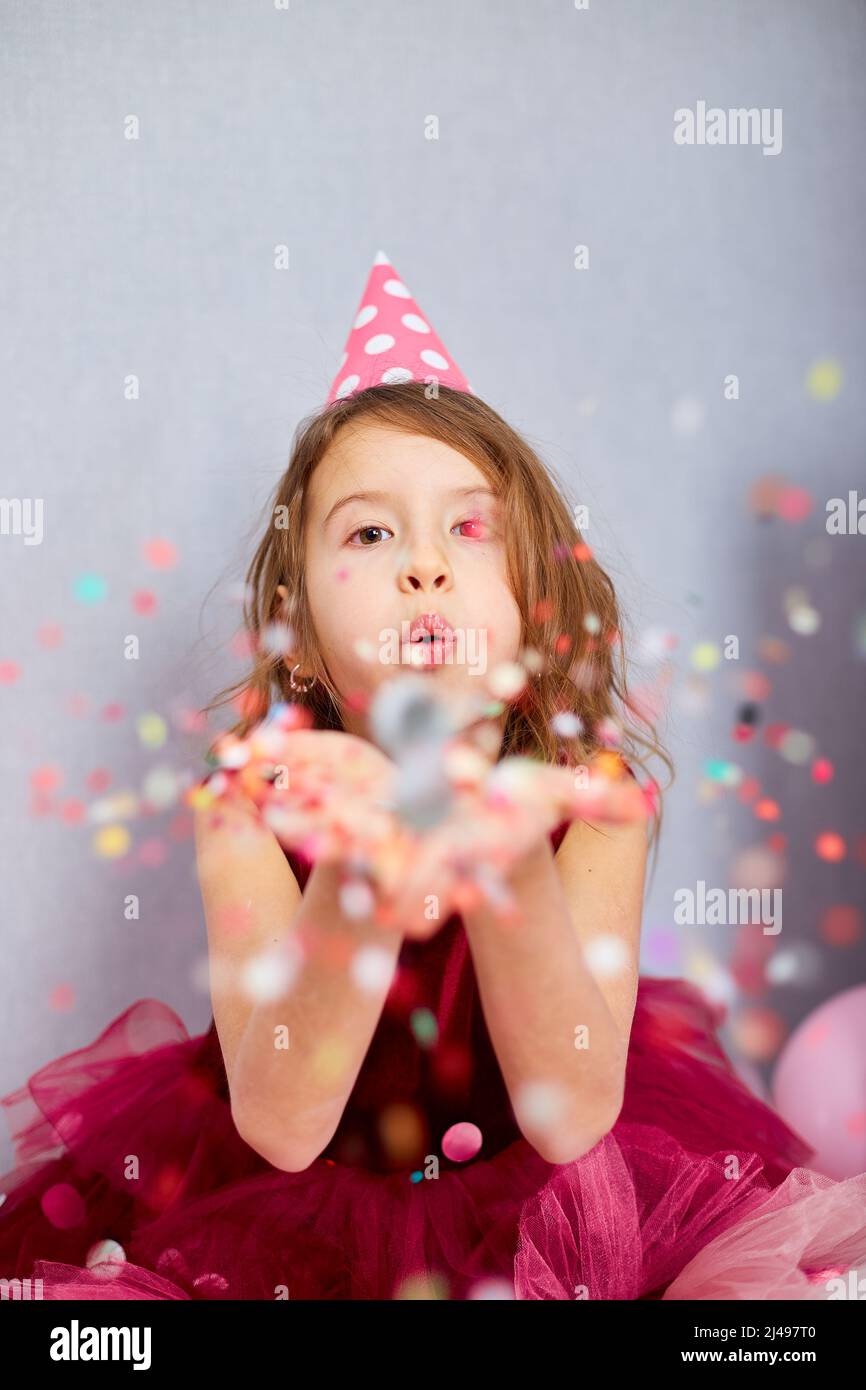 Beautiful little girl blows up multicolored confetti, having fun at