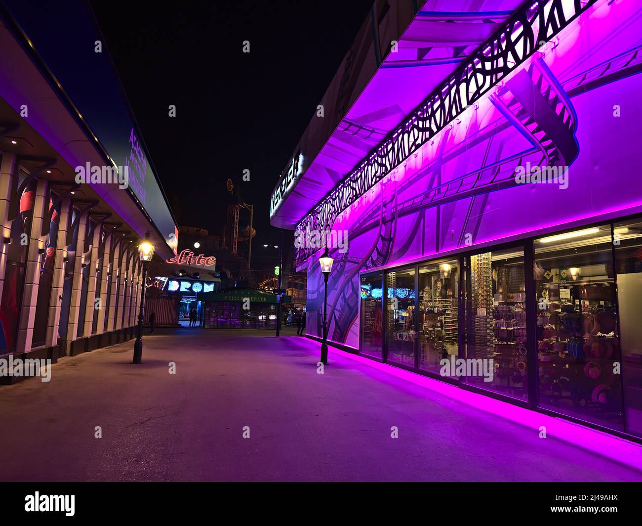 View of empty alley in popular amusement park Wurstelprater near Wiener Prater in Vienna, Austria at night with purple illuminated building. Stock Photo