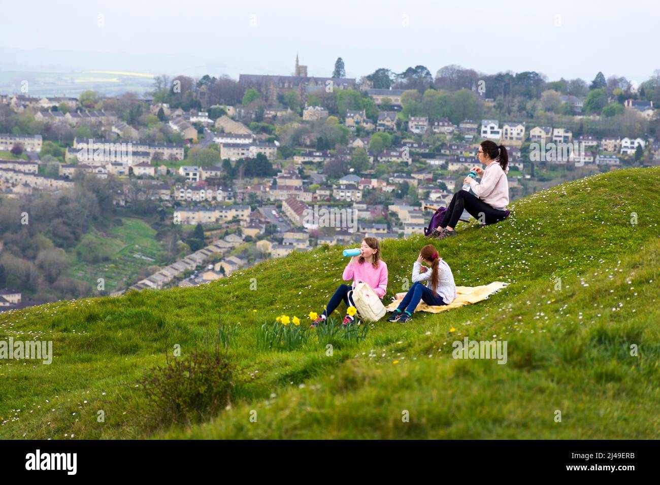 Batheaston, Somerset, UK weather. 13th April 2022. A family take a break after walking to the top of Little Solsbury Hill and admire the view. The former Iron Age fortress hill was made famous in the Peter Gabriel hit song 'Solsbury Hill'. Stock Photo