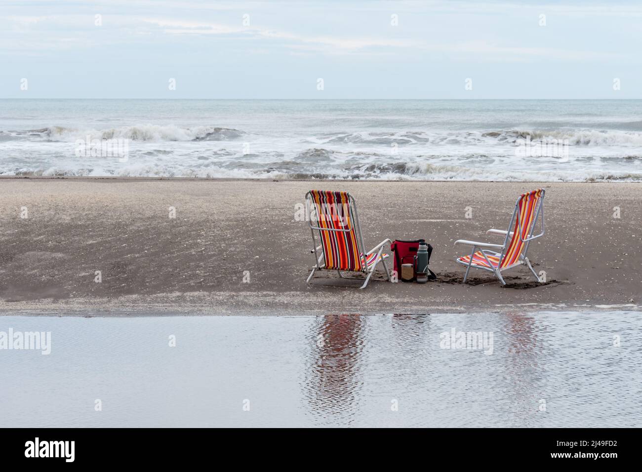 https://c8.alamy.com/comp/2J49FD2/mate-set-bag-yerba-mate-container-mate-and-thermos-next-to-two-beach-chairs-on-the-beach-reflected-in-the-water-2J49FD2.jpg