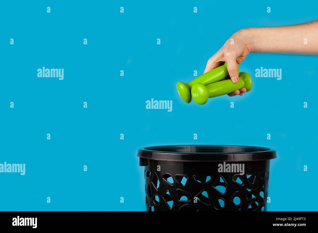 Dumbbells are thrown in the trash can. For copy space for designers on