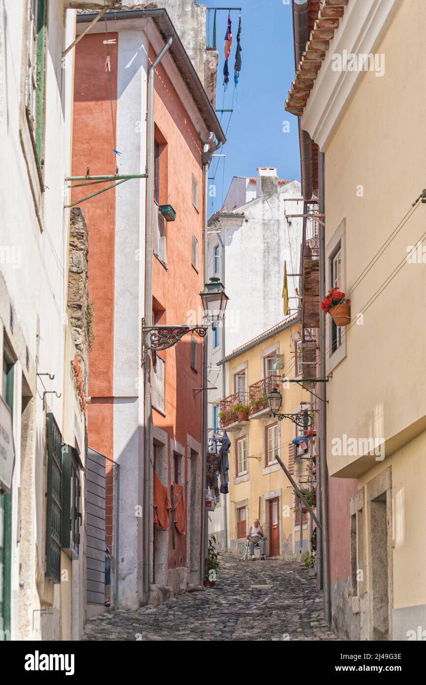 Backstreet at Alfama quarter, Lisbon, Portugal. Old man with crutches