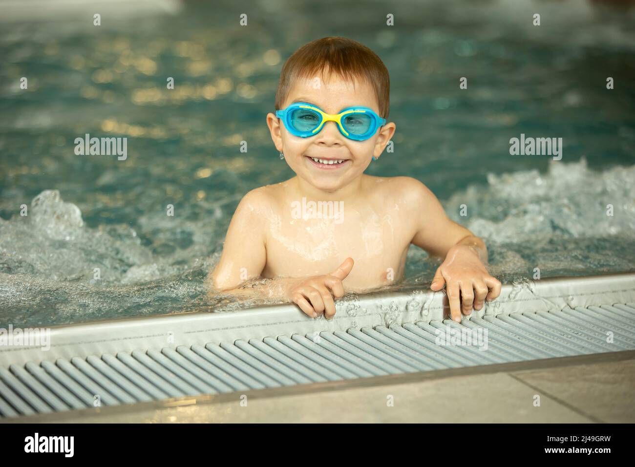 Child, taking swimming lessons in a group of children in indoor pool