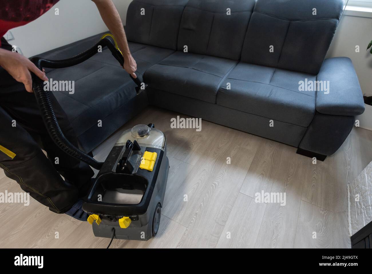 Hand cleaning a sofa with a steam cleaner, Home cleaning concept Stock