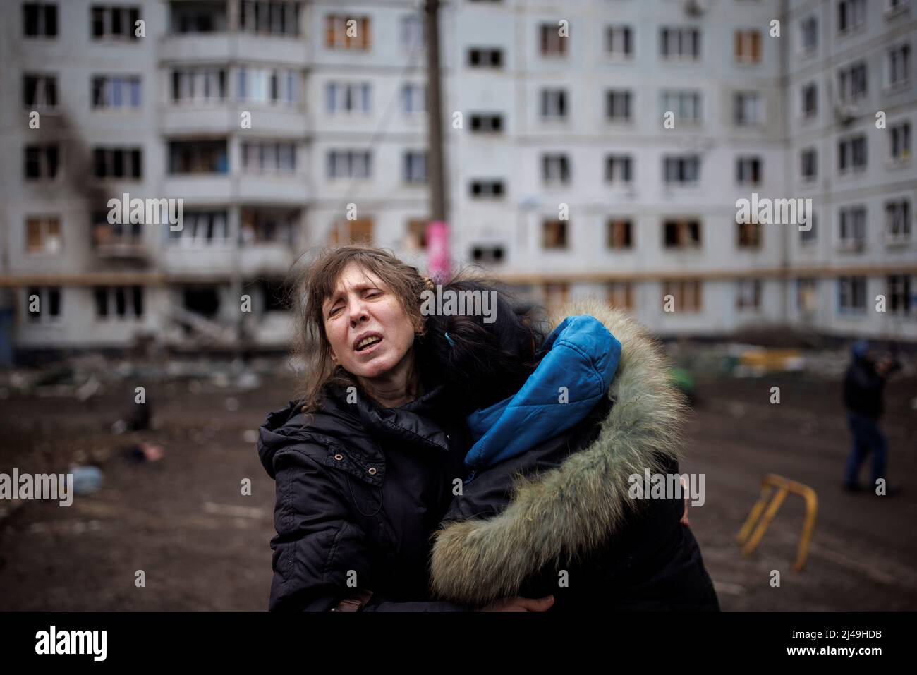 A woman reacts as she hugs another woman outside a heavily damaged  apartment block, following an