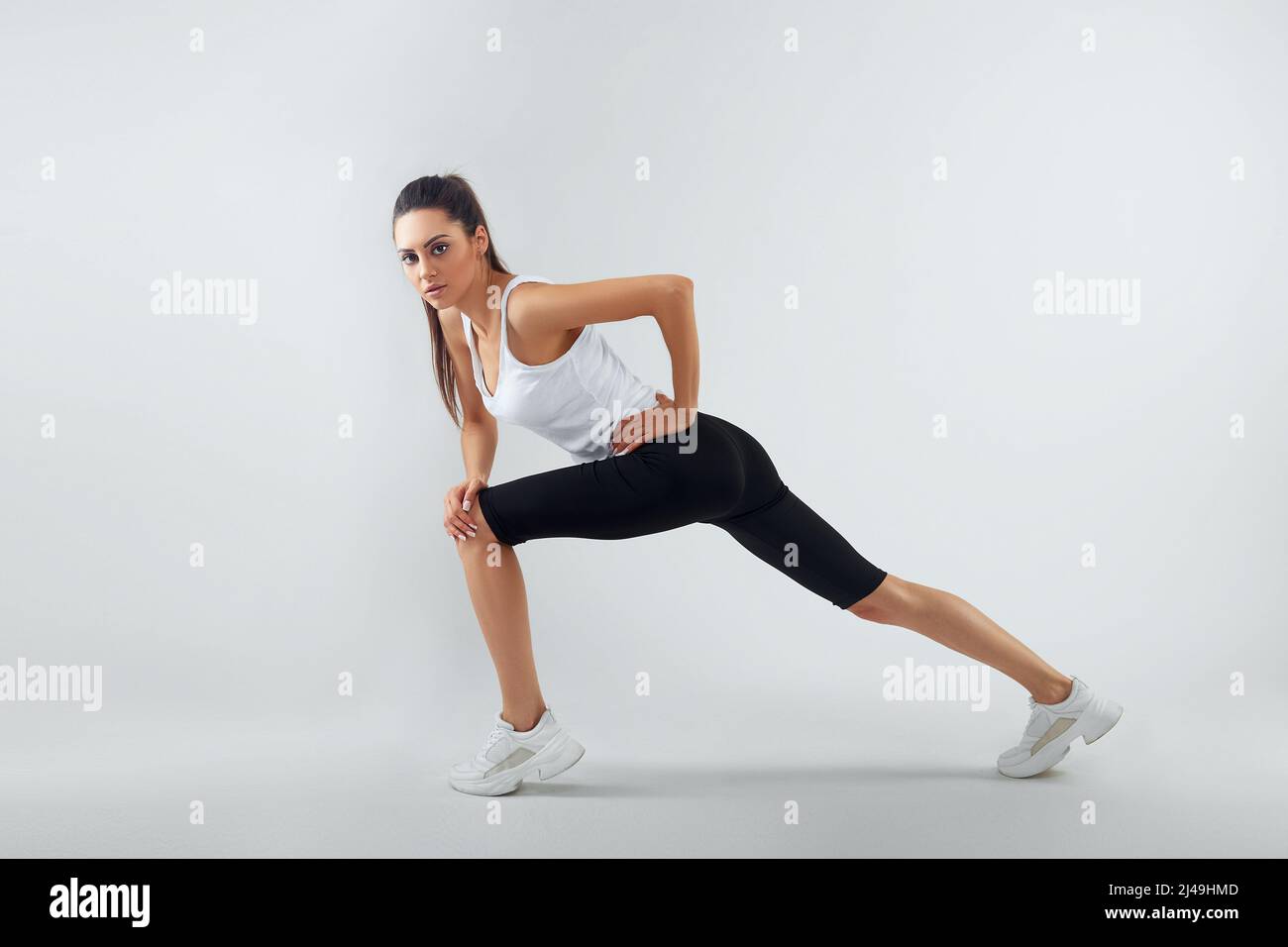 Fit woman stretching her leg to warm up - isolated over background Stock Photo