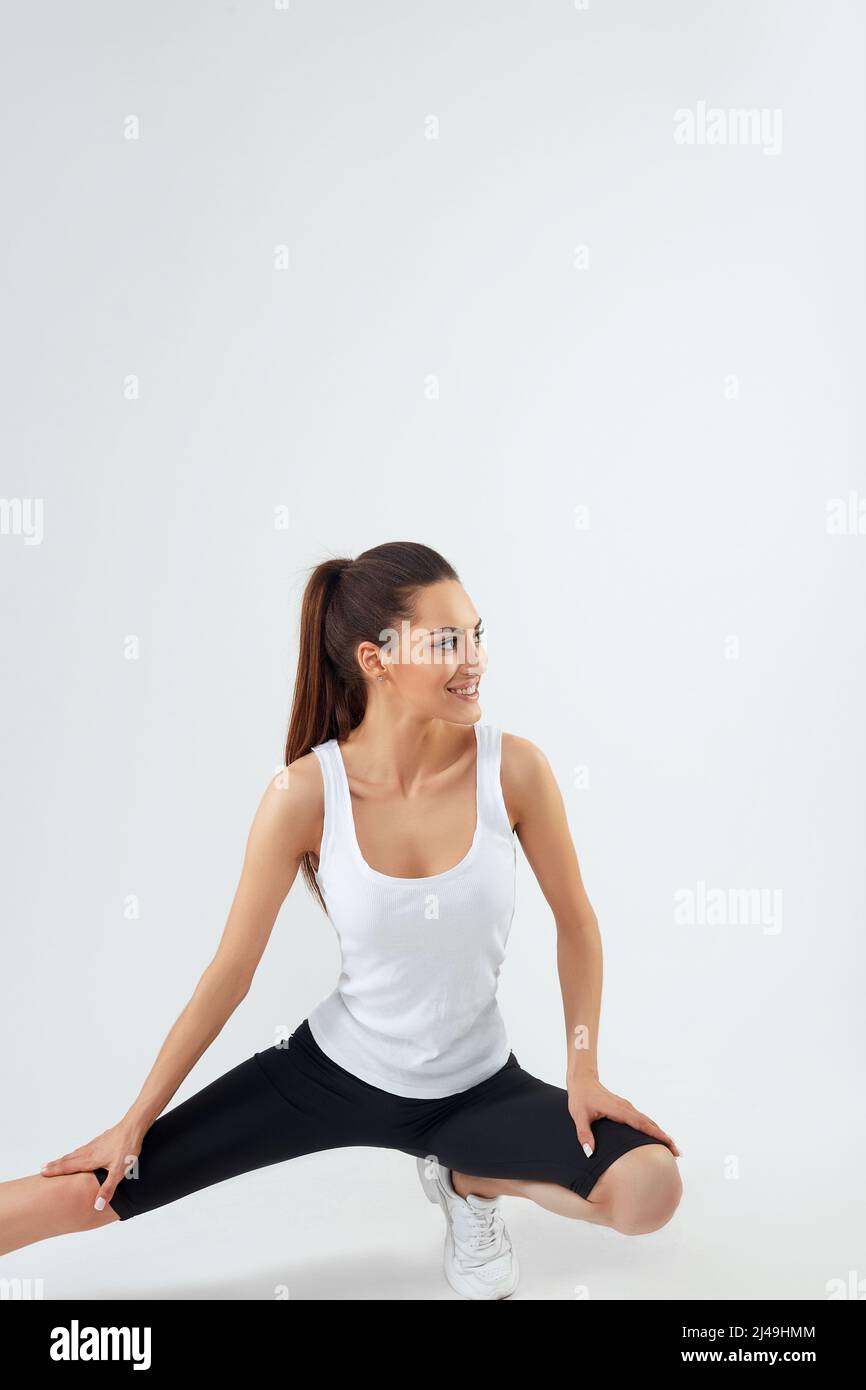 Pretty joyful young sportswoman in tracksuit standing and warming up isolated over grey background Stock Photo