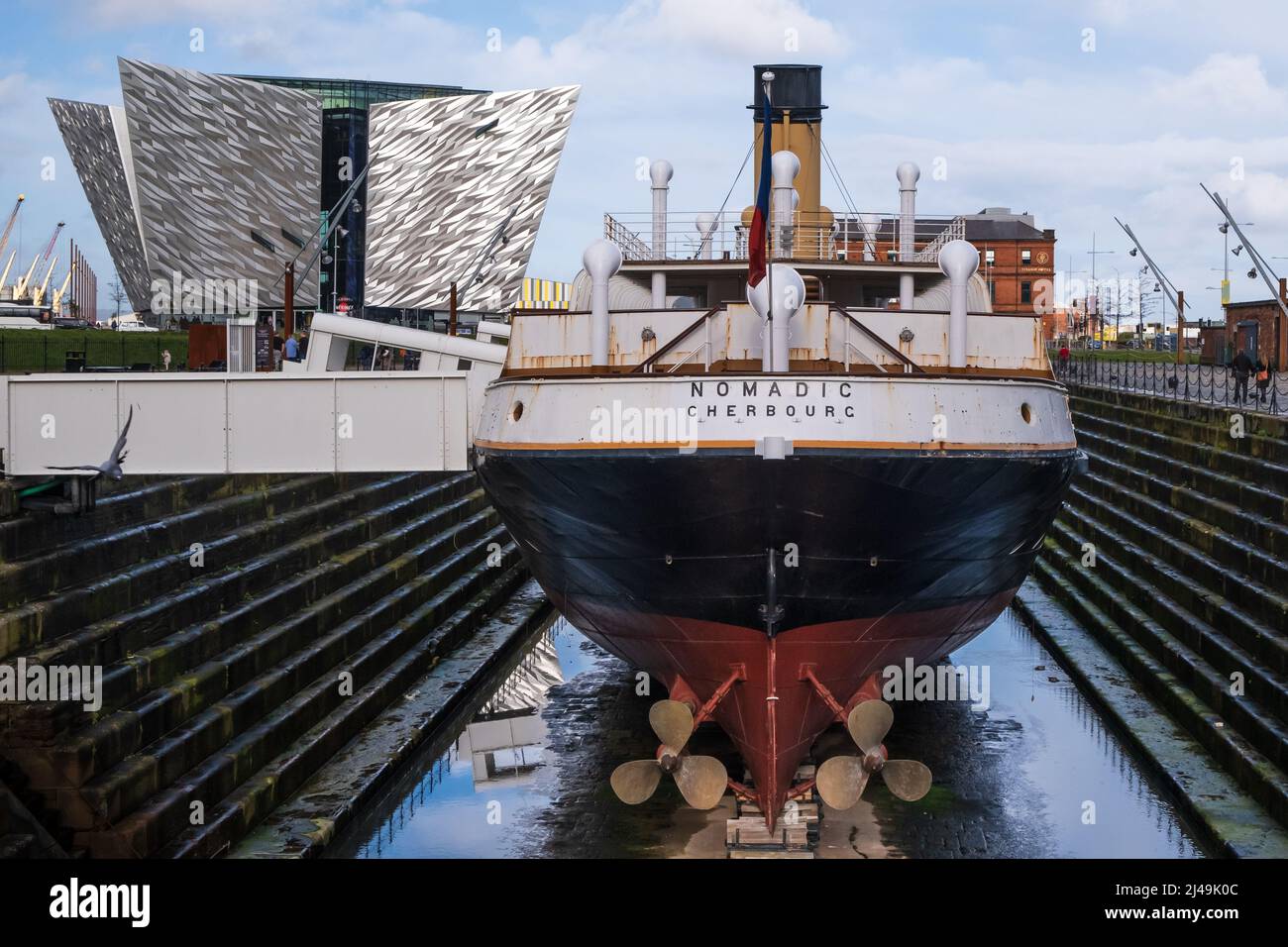 The SS Nomadic in dry dock with the Titanic Hotel and Titanic Building in the background. In the Belfast shipyard area / Titanic Quarter in Belfast, N Stock Photo