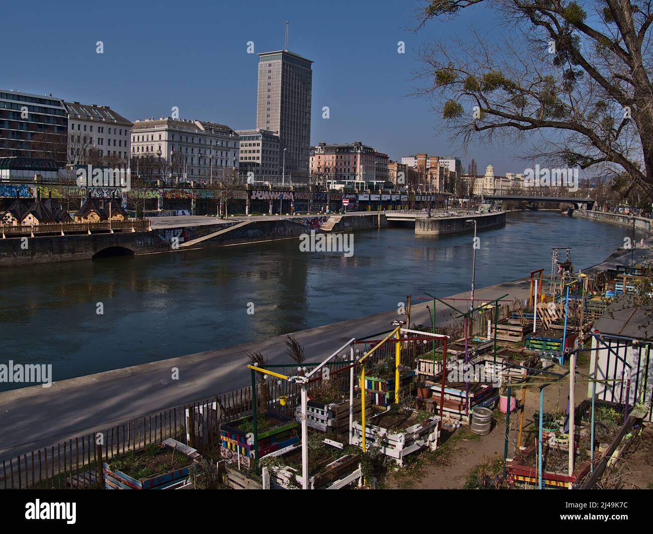 Beautiful view over canal Donaukanal in the downtown of Vienna, Austria with community garden on the riverbank and skyscraper Ringturm on sunny day. Stock Photo