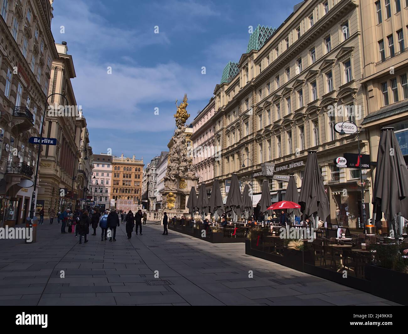 View of busy shopping street Graben in the historic center of Vienna, Austria on sunny day with Plague Column (Trinity Column), cafe and people. Stock Photo