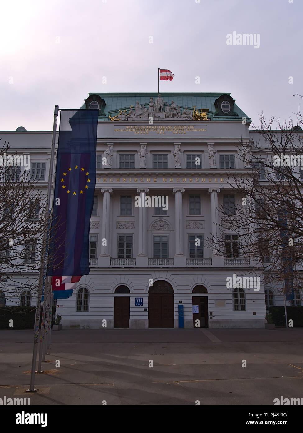 Front view of the main building of university TU Wien in the historic center of Vienna, Austria on cloudy day in spring with logo and flags. Stock Photo