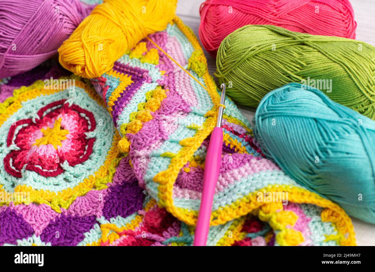 Colorful skeins of yarn arranged next to a crocheted blanket Stock