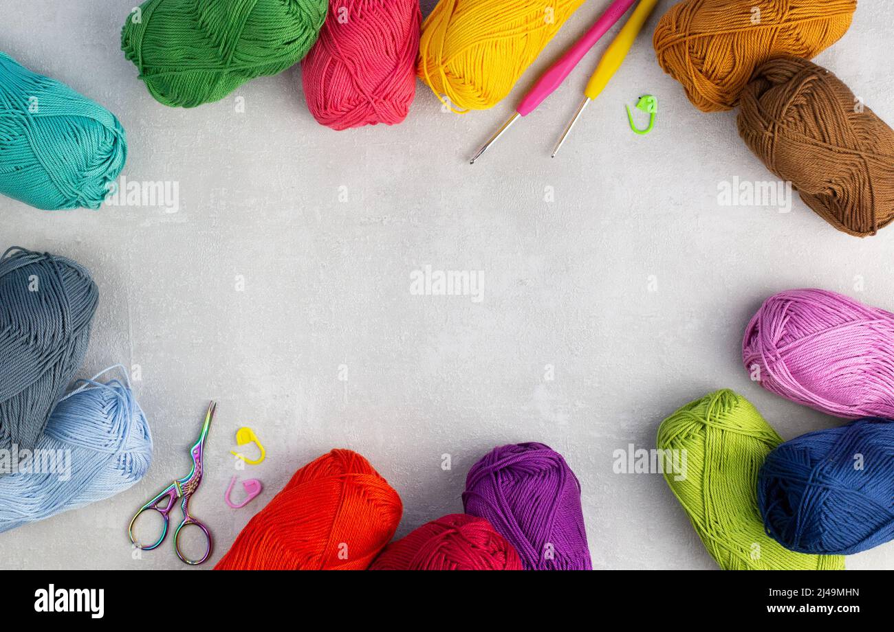 knitting pink crochet hooks and woolen thread on a blue background