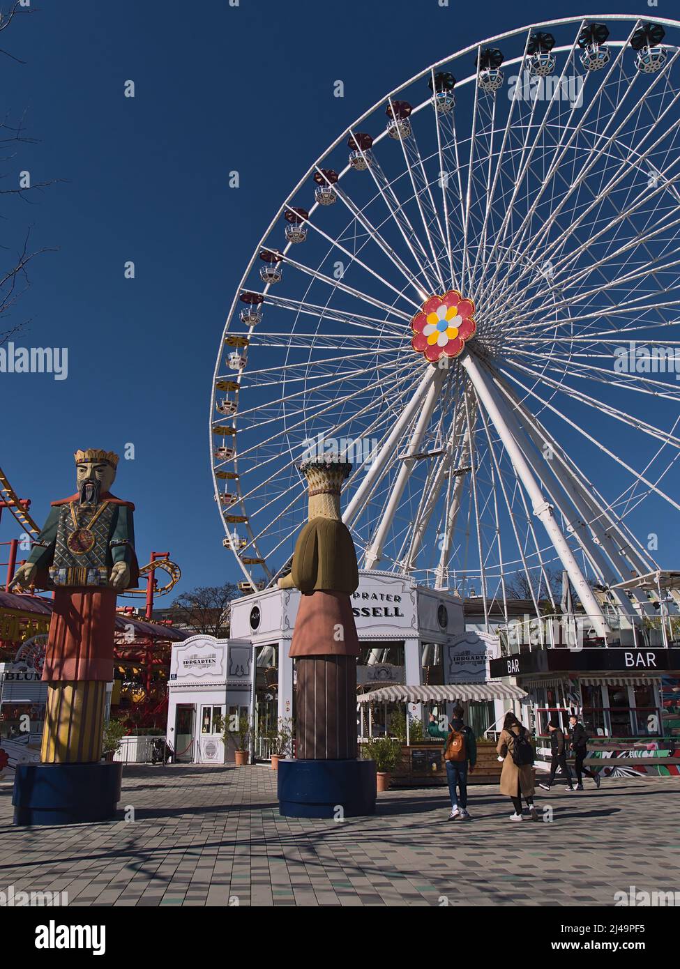 Tourists enjoying their time in popular amusement park Wurstelprater near Wiener Prater in Vienna, Austria with tall ferris wheel Blumenrad. Stock Photo