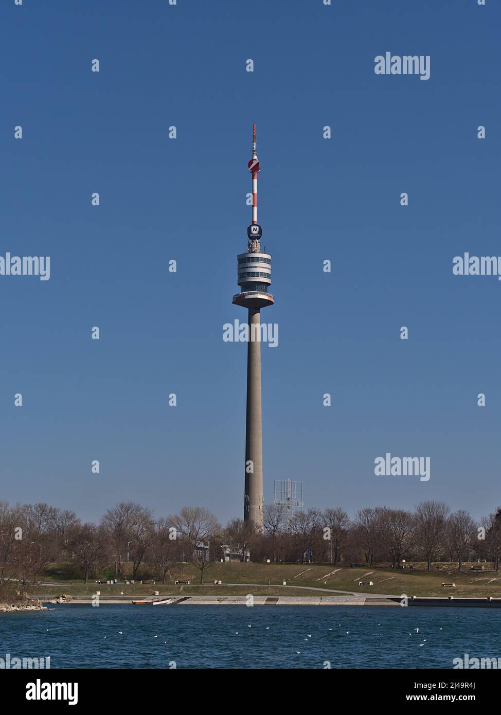 Beautiful view of famous tower Donauturm in Vienna, Austria on the riverbank of Danube River on sunny day in spring season viewed from Danube Island. Stock Photo