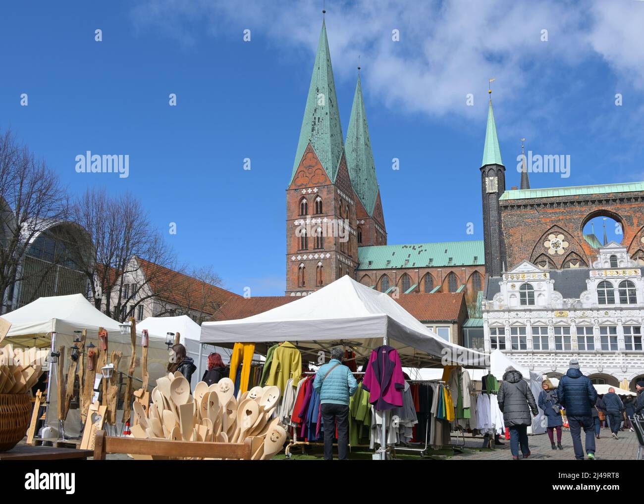 Lubeck, Germany, April 10, 2022: Arts and crafts market with wood products and clothing in tents and stalls in the city center, town hall and St. Mary Stock Photo