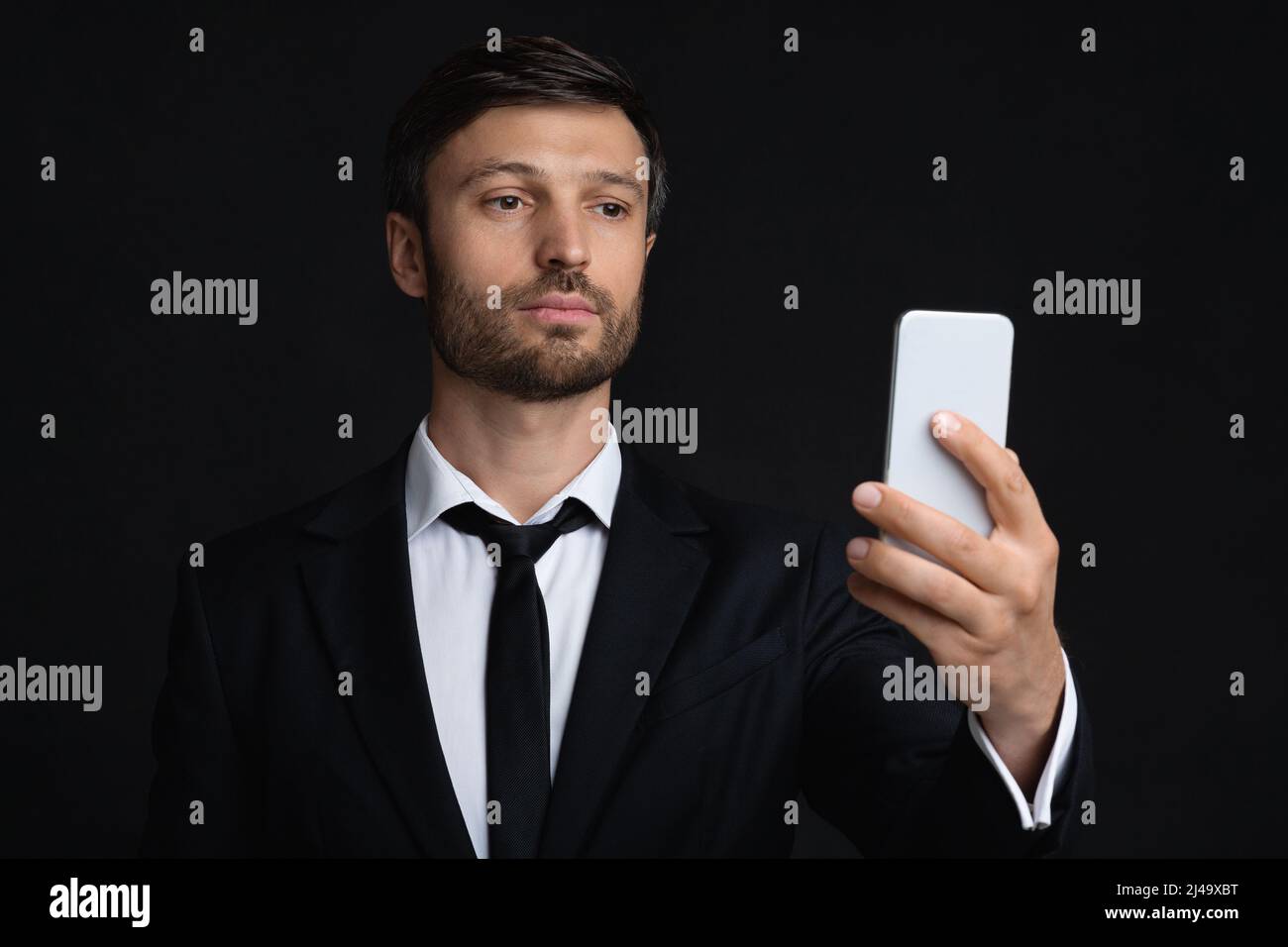 Businessman Using Phone Texting Or Using Mobile Application, Black Background Stock Photo