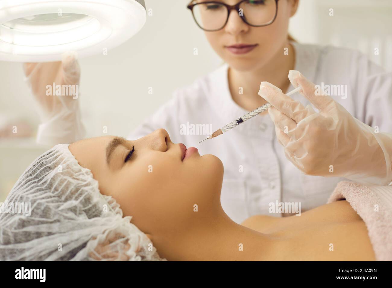 Cosmetologist performs rejuvenating facial injection procedure for her female client. Stock Photo