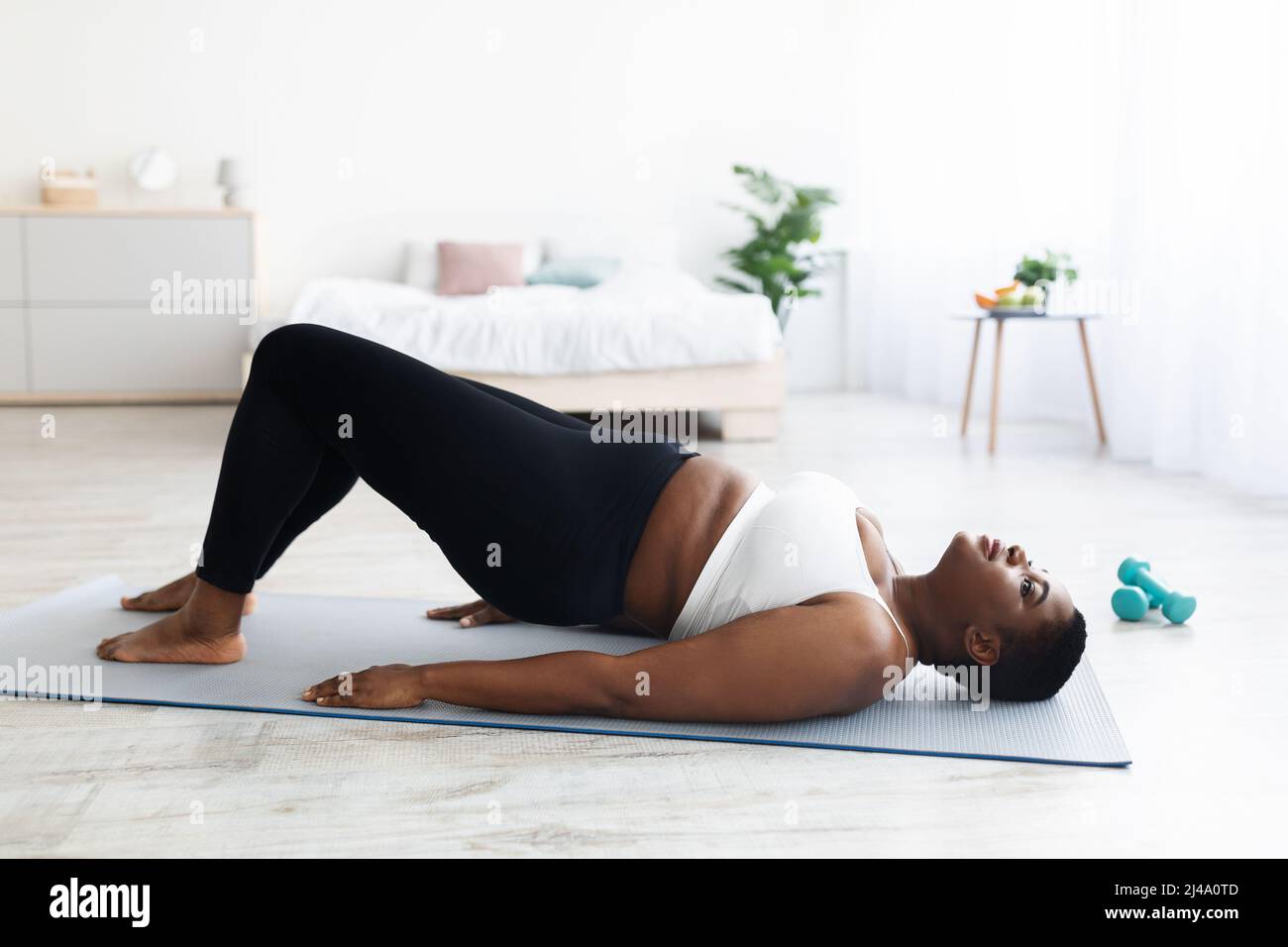 Overweight young black lady doing abs exercises, standing in bridge yoga  pose, training core muscles at home, copy space Stock Photo - Alamy