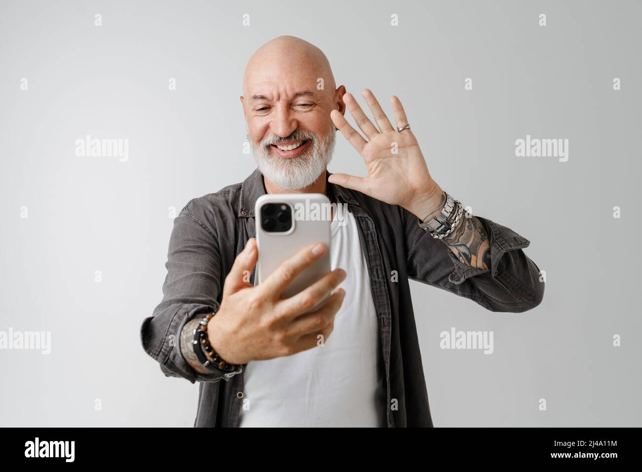 Bald European Man With Beard Gesturing While Taking Selfie On Cellphone 
