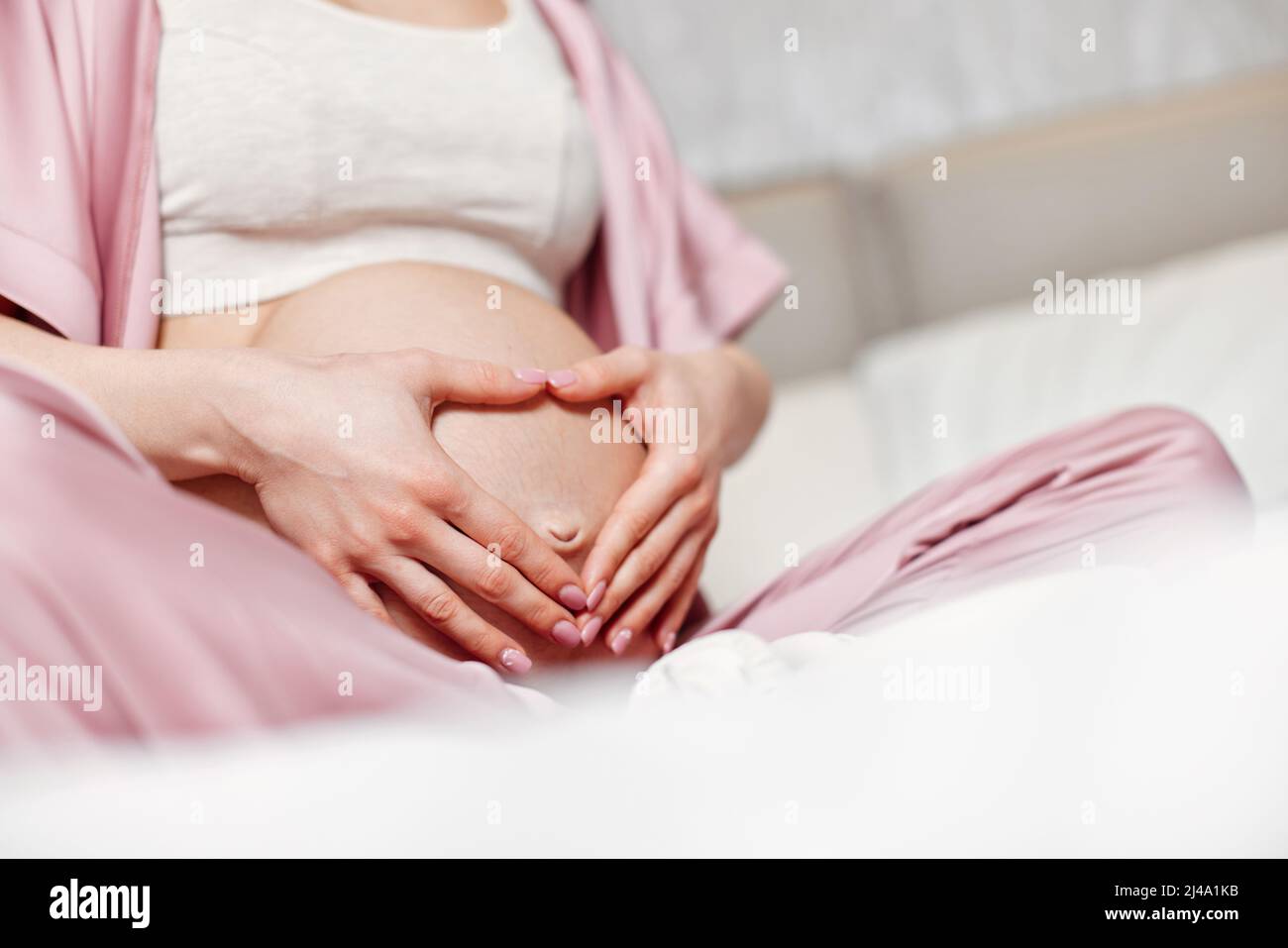 Pregnant woman holding her hands on her belly Stock Photo - Alamy
