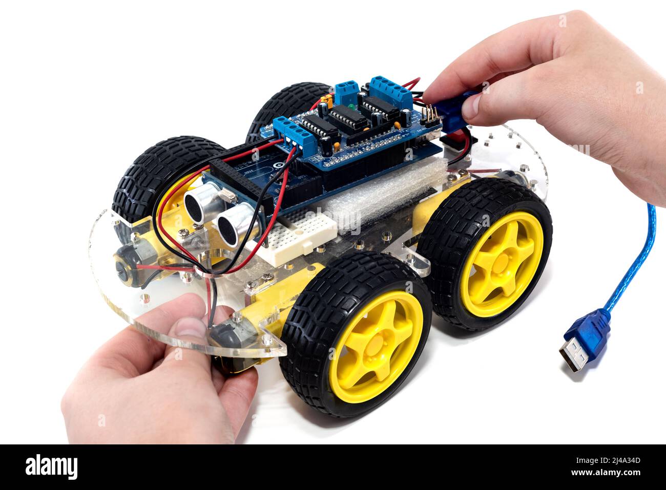 Hands holding programmable robotic car with obstacle avoidance and line following ability, isolated on white background with clipping path. Car on a m Stock Photo