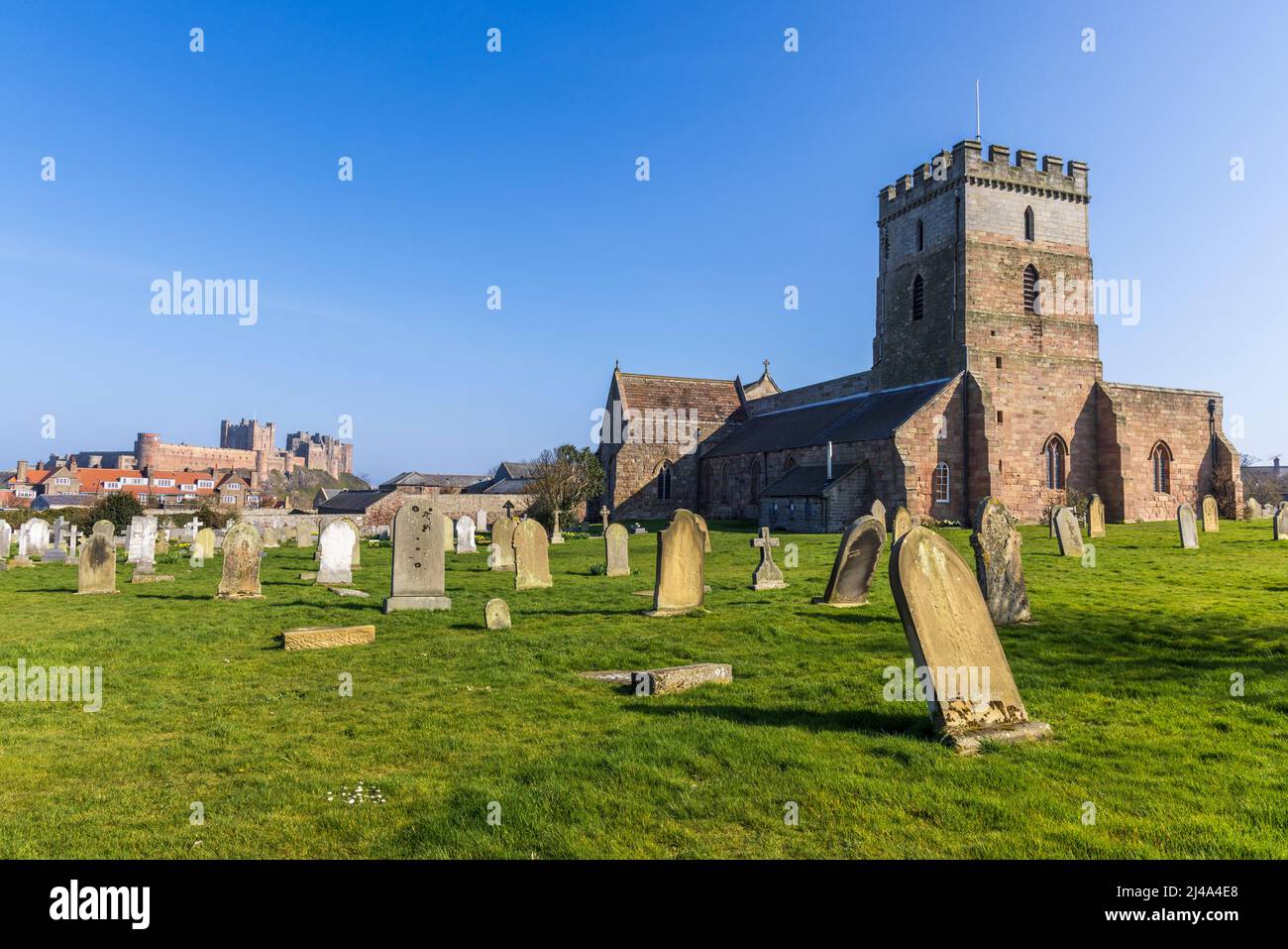 St Aidan Church and graveyard with Bamburgh Castle in the background, Northumberland, England Stock Photo