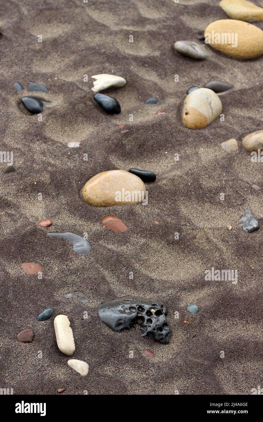 Pebbles of various types, shapes and sizes in the sand. Sandsend beach, Yorkshire Stock Photo